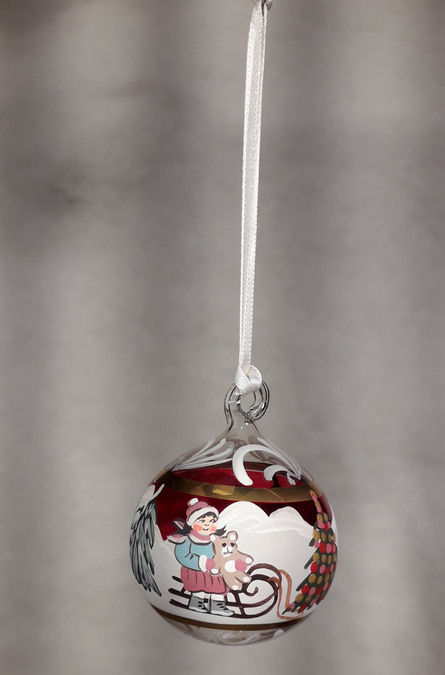 Bimba con slittino e albero di Natale rosso